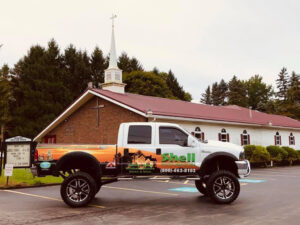 Lifted Shell Restoration branded truck parked outside a church